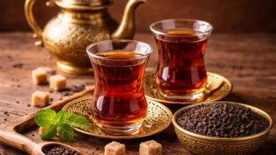 كوبان من الشاي الأسود المحضّر في أكواب زجاجية تقليدية مع أوراق شاي جافة على طاولة خشبية