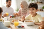 طفل يتناول حبوب الإفطار على مائدة الإفطار مع عائلته في صباح منزلي هادئ
