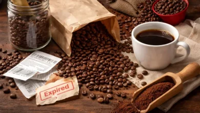 حبوب قهوة مطحونة وحبوب كاملة مع فنجان قهوة على طاولة خشبية