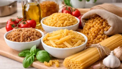 أنواع مختلفة من المكرونة الجافة موضوعة على سطح مطبخ مع مكونات طبخ أساسية