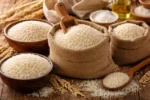 أرز أبيض غير مطبوخ موضوع في أكياس وأوعية على سطح خشبي