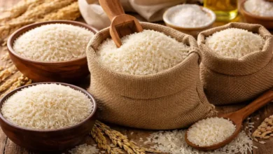أرز أبيض غير مطبوخ موضوع في أكياس وأوعية على سطح خشبي