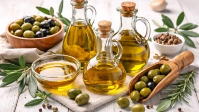 أنواع مختلفة من زيت الزيتون مع زيتون طبيعي على سطح خشبي